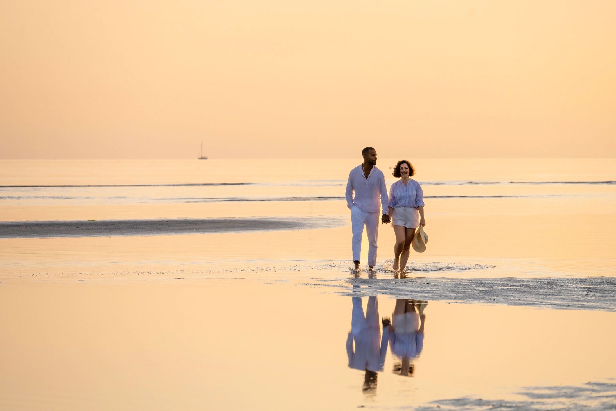 Couple walking along a Caribbean coastline at sunset