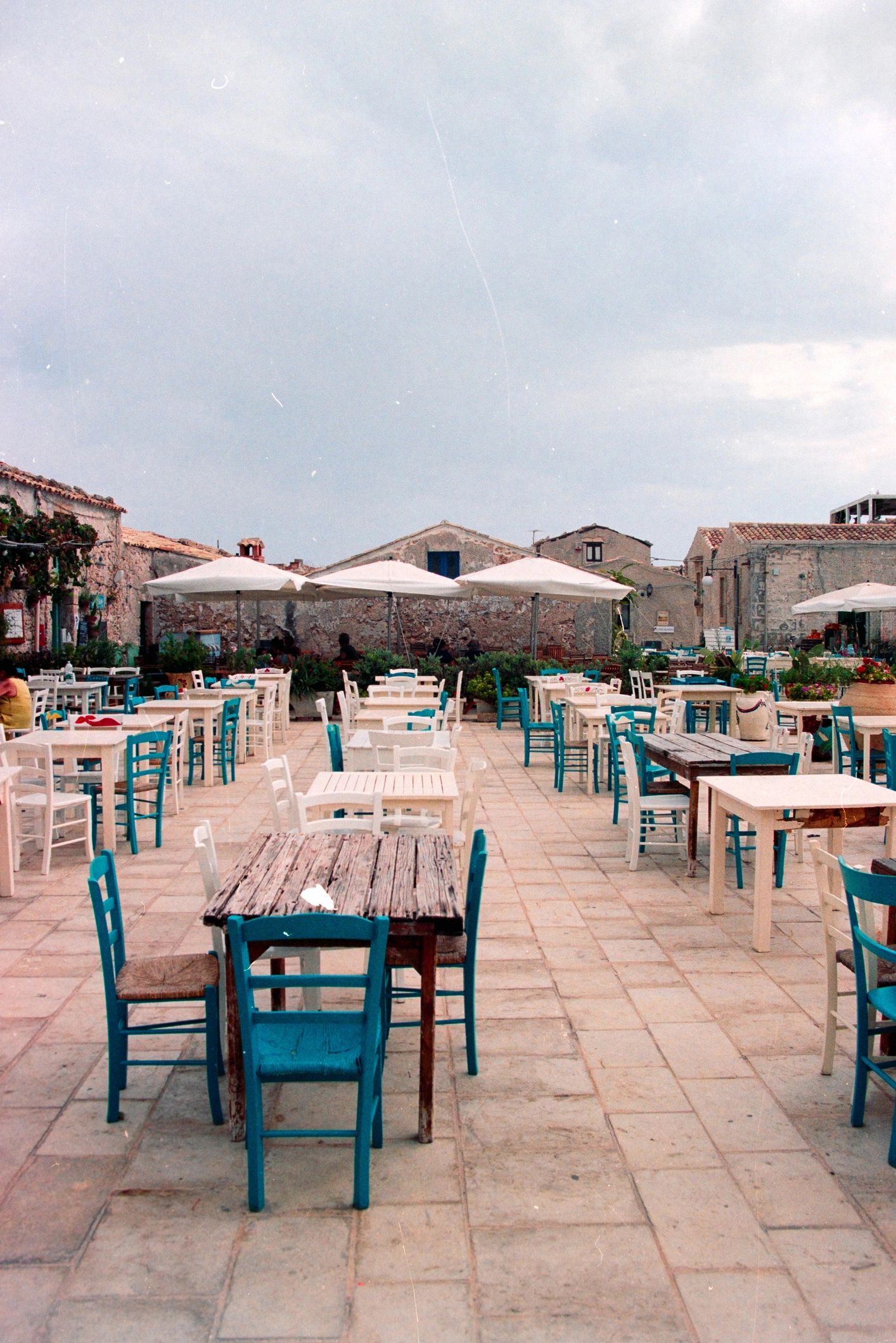 Quiet Mediterranean village square with outdoor cafe tables